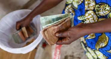 someone paying for their microfinance loan in cash, reflecting the focus of this podcast on the topic of microcredit